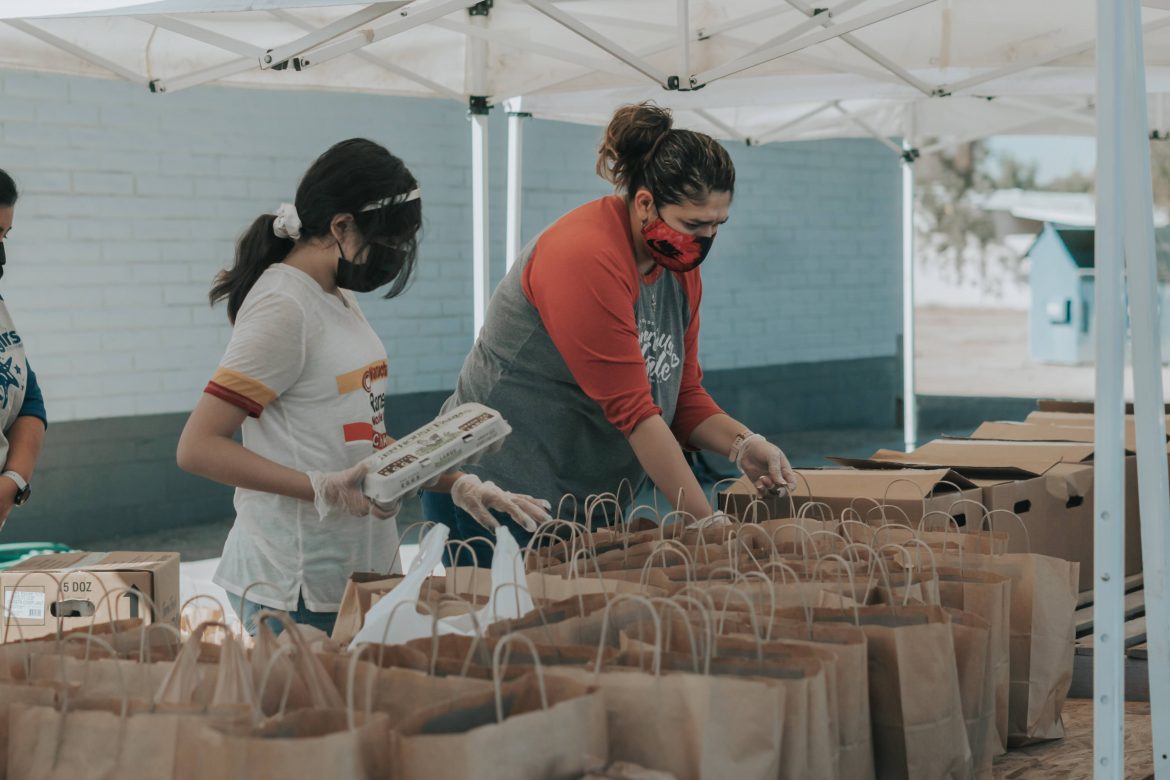 Two volunteers sort food into bags